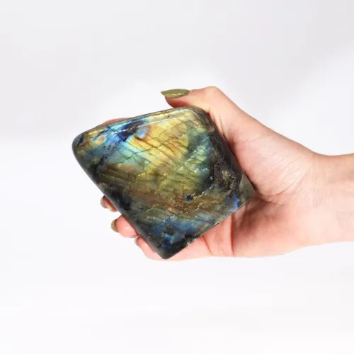 Person tilting labradorite stone under direct light